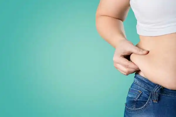 Image of woman pinching her love handles to show weight gain West Drayton